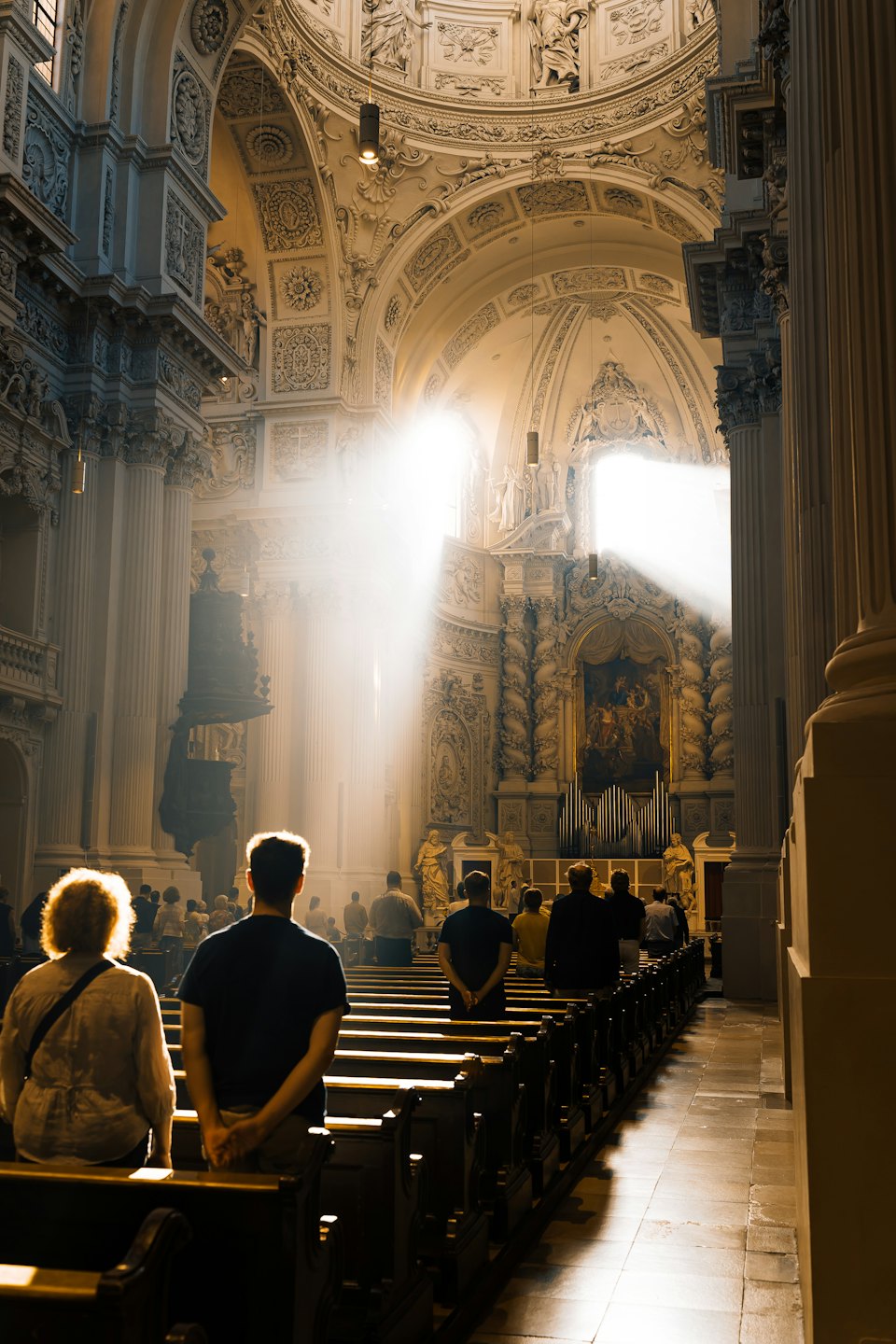 Congregation members sit in the pews of an ornate church.